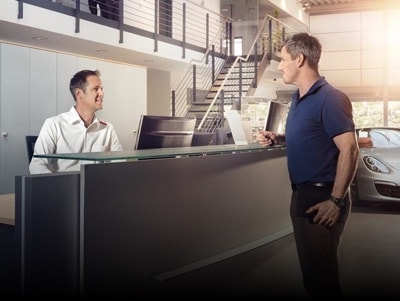 Porsche service advisor helping a client at the service desk